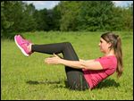 Frau bei Bauchmuskeltraining in einer Wiese