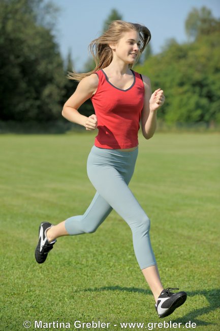 Teenager beim Joggen auf einer Wiese
