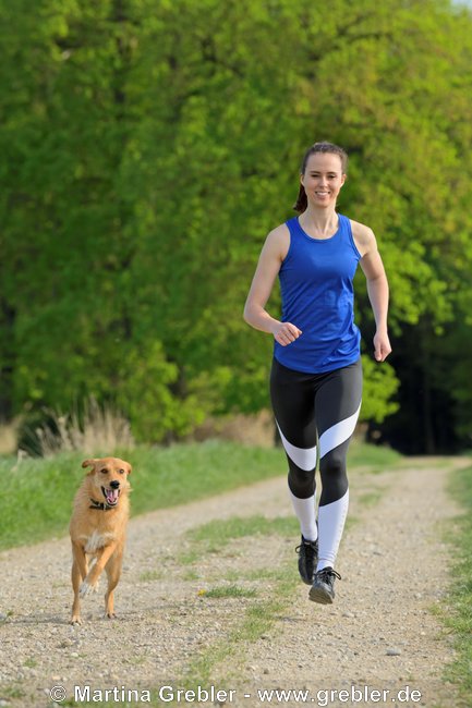 Junge Frau beim Joggen mit ihrem Hund (Mischling) 