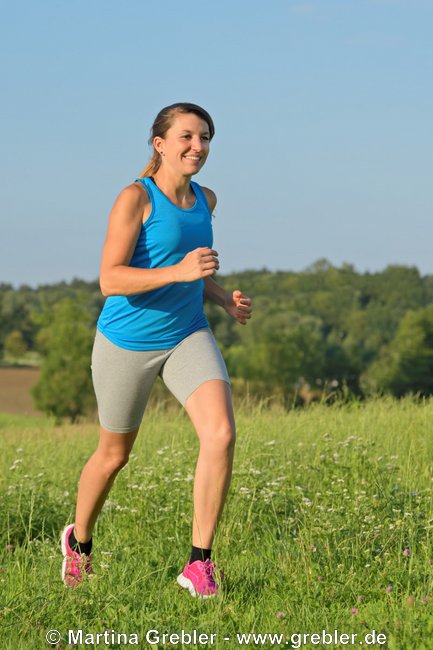 Junge Frau beim Joggen in einer Wiese 