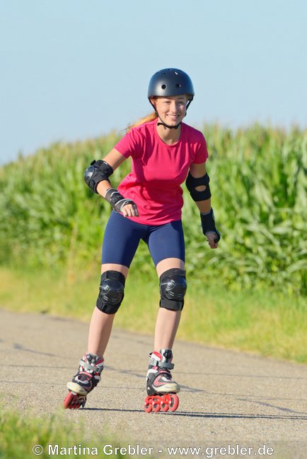 Jugendliche beim Rollerskate fahren mit Helm und Schoner 