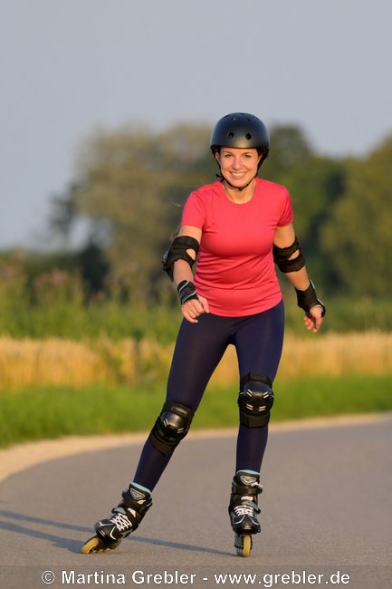 Frau mit Helm und Schoner beim Rollerblading