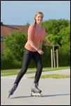 Junge Frau beim Inline Skating auf einer kleinen Straße 