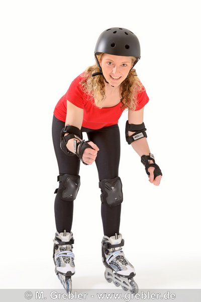 Junge Frau auf Rollerblades (Inlineskates) mit komplettem Satz Schoner (Protektoren) und Helm 
